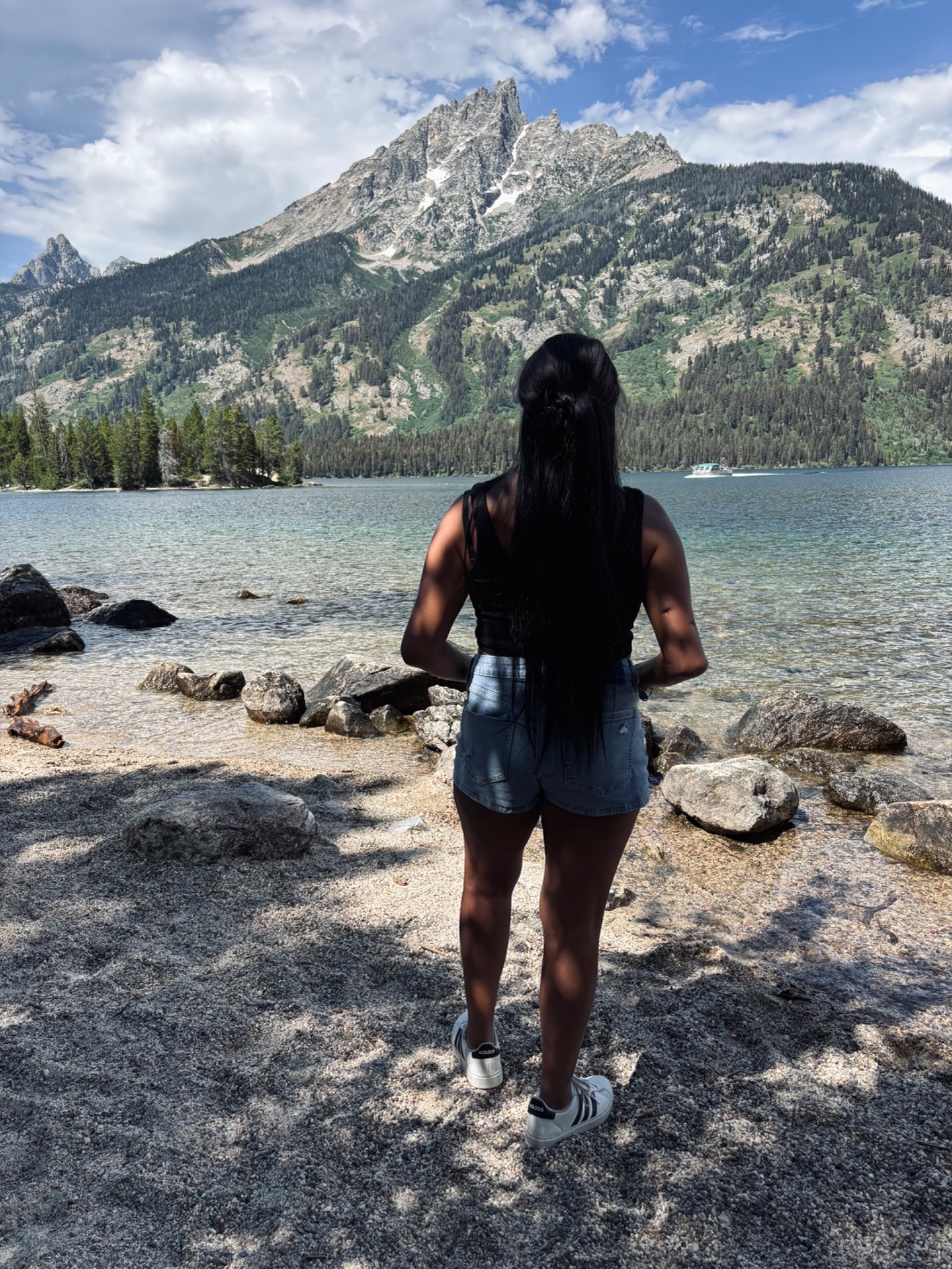 Standing by a lake with the Grand Tetons in the distance